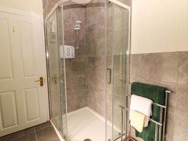 A shower with glass doors and towels in a bathroom at O'Connell's Lodge, Portmagee, County Kerry