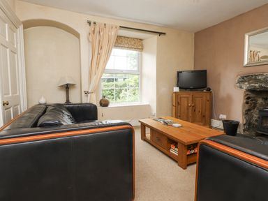 A living room with a television and coffee table at Sygun Cottage in Nant Gwynant