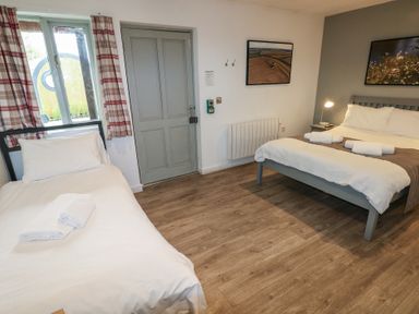 A bedroom with one single bed and one double bed with towels on them at Beech in Cowbridge