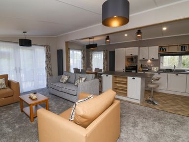 An open plan living room with sofas a coffee table kitchen and dining area at 16 Manleigh Park in Combe Martin