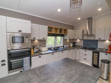A kitchen with white cabinets a built-in oven microwave and stovetop at 16 Manleigh Park Combe Martin