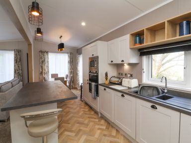A kitchen with white cabinets a dining area and a stool at 16 Manleigh Park Combe Martin