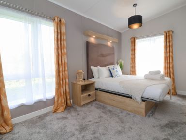 A bedroom with a double bed nightstand and orange curtains at 16 Manleigh Park in Combe Martin