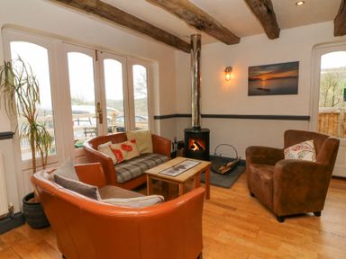 A sitting area with armchairs around a small wooden table and a wood burning stove at 16 Manleigh Park in Combe Martin