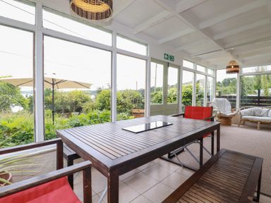A conservatory with a wooden table and chairs at Nanvivian in Feock near Truro