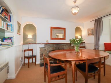 A dining room with a table and bookshelf at Nanvivian in Feock near Truro