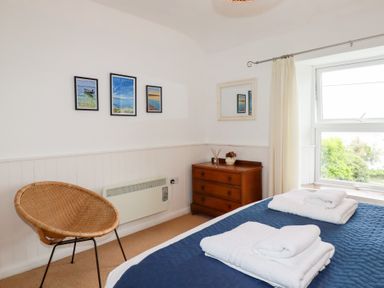 A bedroom with a bed, chair, and artwork on the wall at Nanvivian in Feock near Truro