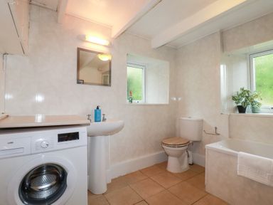 A bathroom with a washing machine, sink, and bathtub at Nanvivian in Feock near Truro