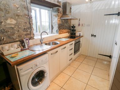 A kitchen with a washing machine and stove at 8 Rogeston Cottages Haverfordwest