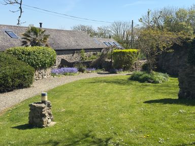 A garden with flowers and a stone wall at 8 Rogeston Cottages Haverfordwest