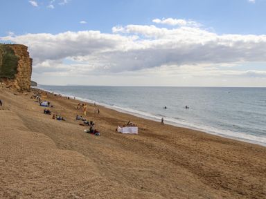 A beach with people relaxing and surfing at Flat 13, Chesil House in Bridport