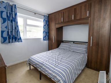 A bedroom with a bed and wardrobes at Beachcombers, 13 Chesil House, Bridport