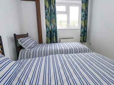 A bedroom with two beds and a window at Beachcombers, 13 Chesil House in Bridport
