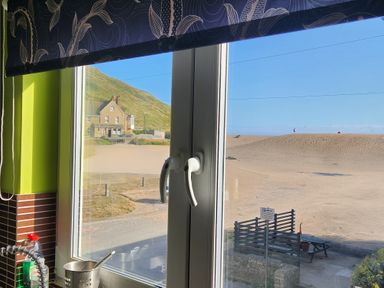 A kitchen window overlooking a beach at Beachcombers, 13 Chesil House, West Bay