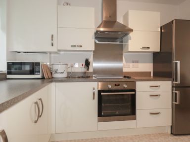 A kitchen with white cabinets a microwave a bread container a knife set an oven a stainless steel stove hood and a refrigerator at 13 Clock Tower Court in Charlestown