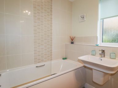 A bathroom with a bathtub a sink tiles on walls and a window at 13 Clock Tower Court Charlestown