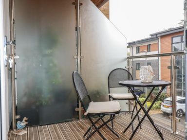 A balcony with two chairs and a round table with a decorative item at 13 Clock Tower Court in Charlestown