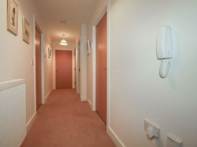 A hallway with wooden doors white walls a wall-mounted telephone and framed pictures at 13 Clock Tower Court in Charlestown
