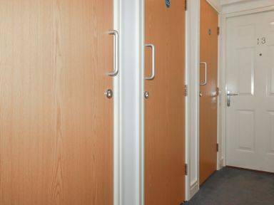 A hallway with three wooden doors and one white door with the number 13 at 13 Clock Tower Court in Charlestown