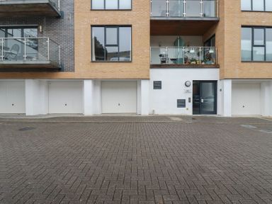 The exterior of a modern apartment building with multiple garage doors a glass entrance door and balconies above at 13 Clock Tower Court in Charlestown