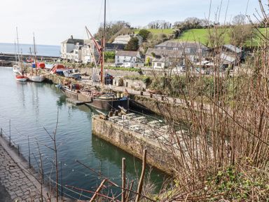 A harbor with several docked boats next to stone buildings and grassy hills at 13 Clock Tower Court in Charlestown