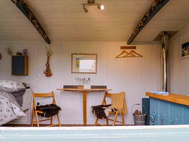 A small dining area with two wooden chairs and a foldable table in a cabin at Oak Shepherd Hut in Monkton Wyld near Charmouth