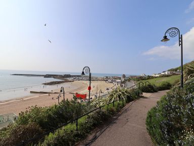 A beach with people near the sea and a path with street lamps overlooking the shoreline at Oak Shepherd Hut in Monkton Wyld near Charmouth