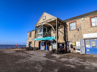 Exterior view of Charmouth Heritage Coast Centre with benches motorcycle and sea in background