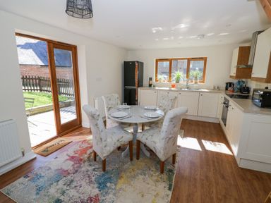 A kitchen with a round dining table set for four and floral upholstered chairs at Little Barn in Dodwell near Stratford-Upon-Avon