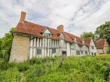 A historic half timbered house with red tiled roof and greenery in front at Little Barn in Dodwell near Stratford-Upon-Avon