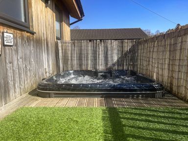 An outdoor area with a hot tub at Woodburn Lodge in Otterburn