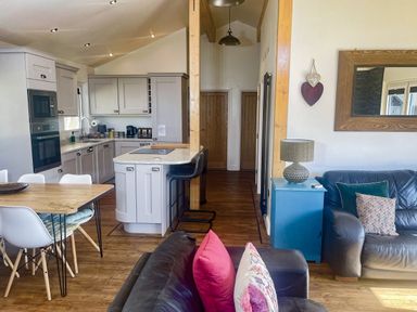 A kitchen with a table and chairs and a sofa at Woodburn Lodge in Otterburn