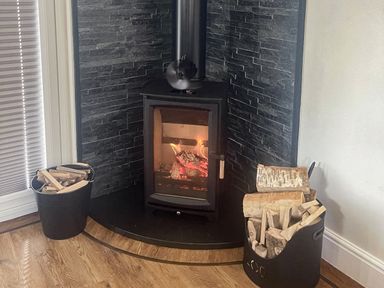 A fireplace with logs and a metal bucket at Woodburn Lodge in Otterburn
