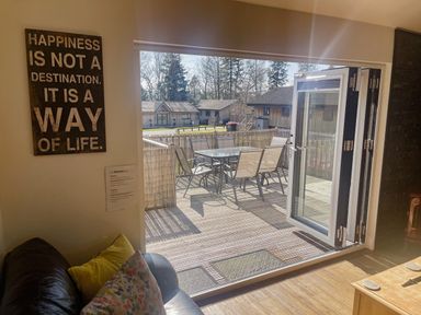 A living room with bifold doors leading to a deck at Woodburn Lodge in Otterburn