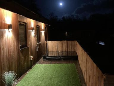 An outdoor area with a hot tub and artificial grass at Woodburn Lodge Otterburn