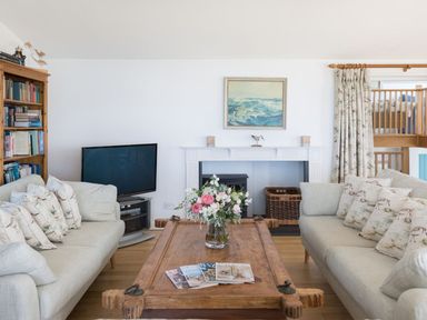 A living room with two sofas facing a wooden coffee table with flowers and magazines at Splits in Daymer Bay