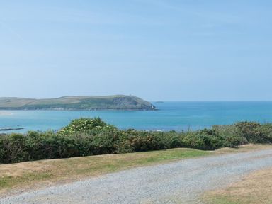 A coastal landscape with a gravel path and vegetation overlooking the sea and a distant island at Splits in Daymer Bay