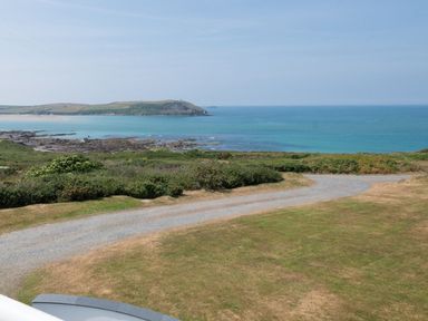 A coastal view with a gravel path green shrubs and blue sea at Splits in Daymer Bay