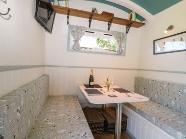 A small dining area with a white table and cushioned bench seating on both sides at Songbirds in St Michaels Kent
