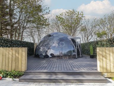 A transparent geodesic dome on a wooden deck surrounded by hedges and trees at Number 1 Dome in Derrybeg County Donegal