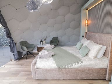 A bedroom with a bed green chairs and a small round table inside a geodesic dome at Number 1 Dome in Derrybeg County Donegal