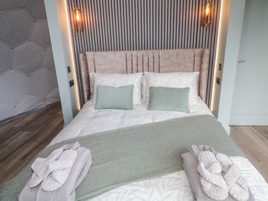 A bedroom with a bed two pillows two cushions two hanging lights and slippers on a bed at Number 1 Dome in Derrybeg County Donegal