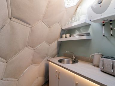 A kitchenette with a sink toaster kettle shelves with cups plates and glasses at Number 1 Dome in Derrybeg County Donegal