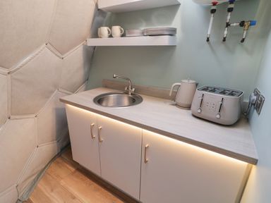 A kitchenette with a sink kettle toaster shelves with mugs and plates at Number 1 Dome in Derrybeg County Donegal