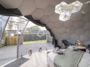A bedroom inside a dome structure with a bed covered with a green blanket two chairs and a round table at Number 1 Dome in Derrybeg County Donegal