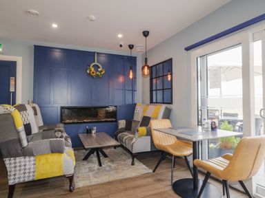 A sitting area with patchwork armchairs and a blue paneled wall with an electric fireplace at Number 1 Dome in Derrybeg County Donegal