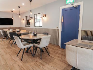 A dining area with round and square tables and chairs a blue door and wall mirrors at Number 1 Dome in Derrybeg County Donegal