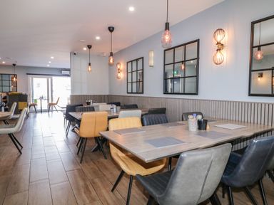 A dining area with tables and mixed color chairs pendant lights and wall mirrors at Number 1 Dome in Derrybeg County Donegal
