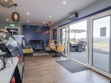 A cafe seating area with tables chairs a blue accent wall and large sliding glass doors at Number 1 Dome in Derrybeg County Donegal