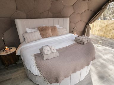 A bedroom with a round bed with pillows bedside tables and wooden flooring at Number 2 Dome in Derrybeg County Donegal